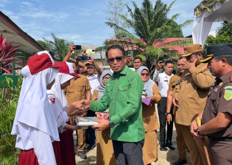 Ketua DPRD SBT Risman Sibualamo menyerahkan paket MBG kepada siswa-siswi SD Negeri 6 Bula (Dok : Pribadi)